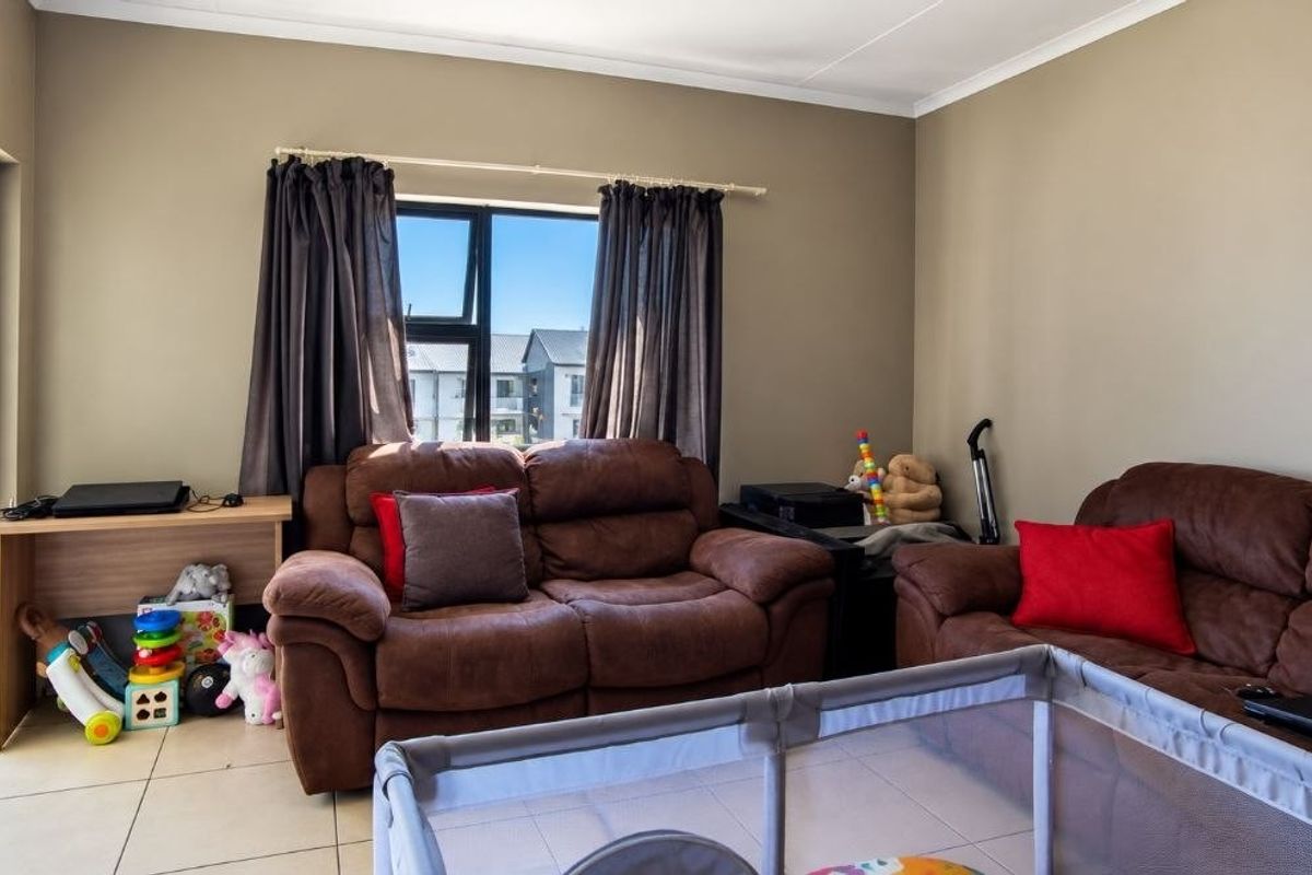 A living room featuring neutral wall tones, tiled flooring, and a large sliding glass door providing access to an outdoor area.
