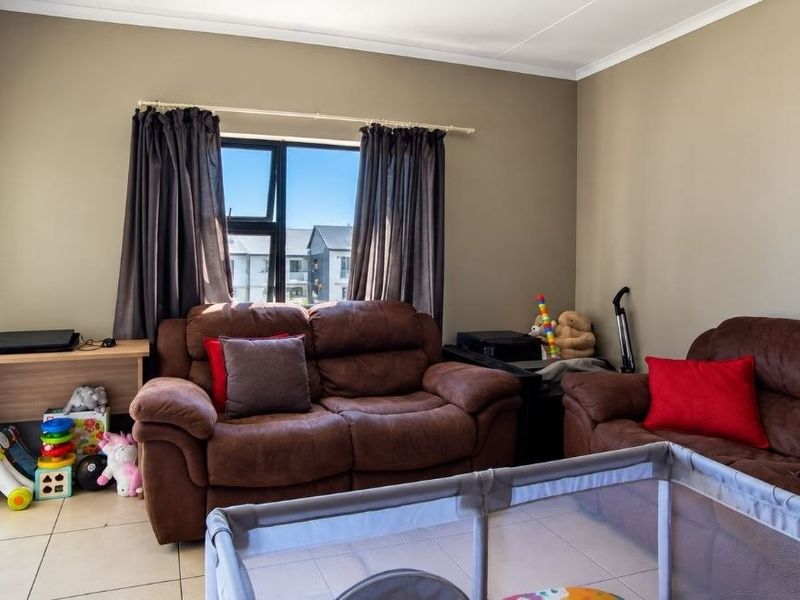 A living room featuring neutral wall tones, tiled flooring, and a large sliding glass door providing access to an outdoor area.