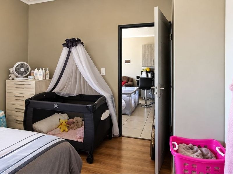 A bedroom featuring laminate flooring, built-in wardrobe storage, and a doorway leading to an adjacent living area.