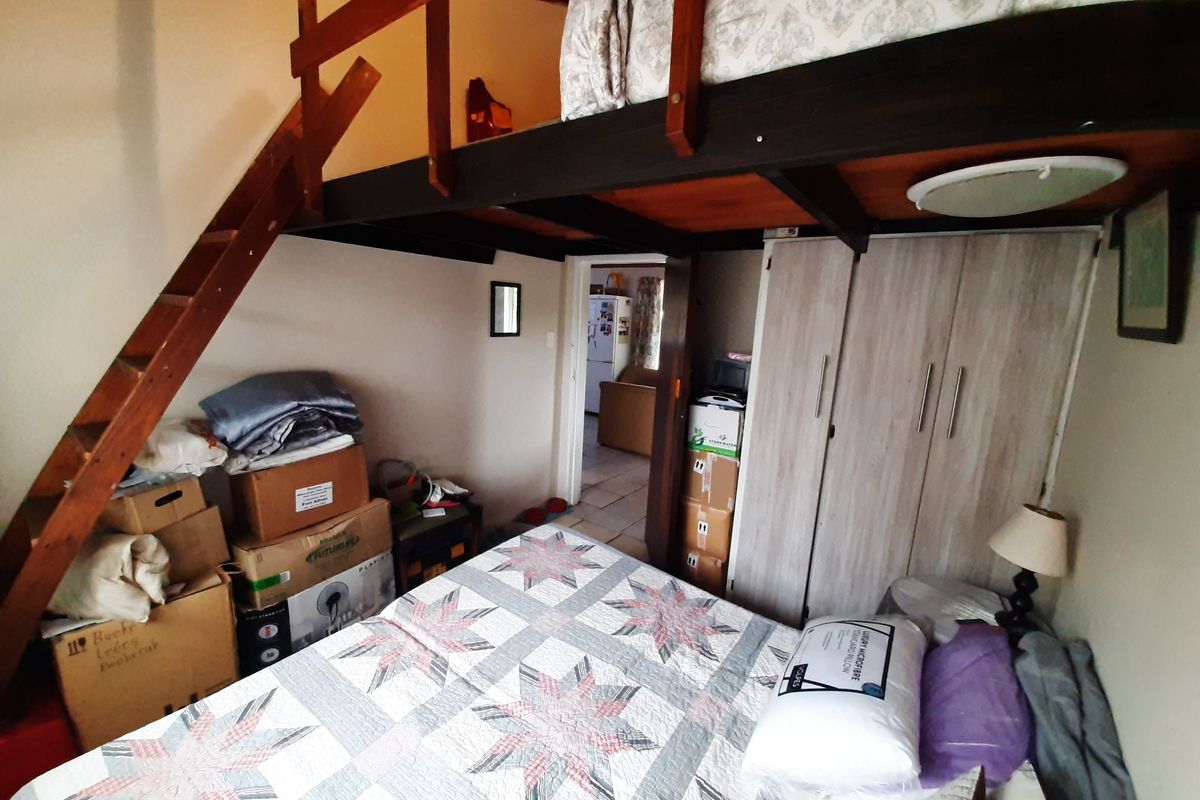 Bedroom featuring a built-in wardrobe and a wooden mezzanine loft level with an integrated staircase, offering additional vertical space.