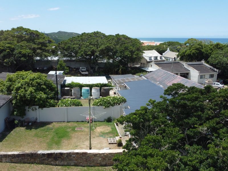 Aerial view of the property showing the roof structure, surrounding garden area, boundary walls, and proximity to the coastline.
