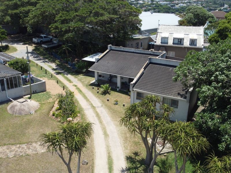 Aerial view of the townhouse property featuring a tiled roof, covered patio, and surrounding garden area with a gravel driveway.