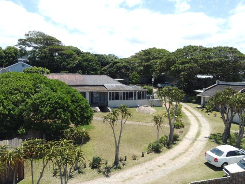 Aerial view of a townhouse property featuring a large garden, gravel driveway, and a structure with a corrugated metal roof and enclosed patio area.
