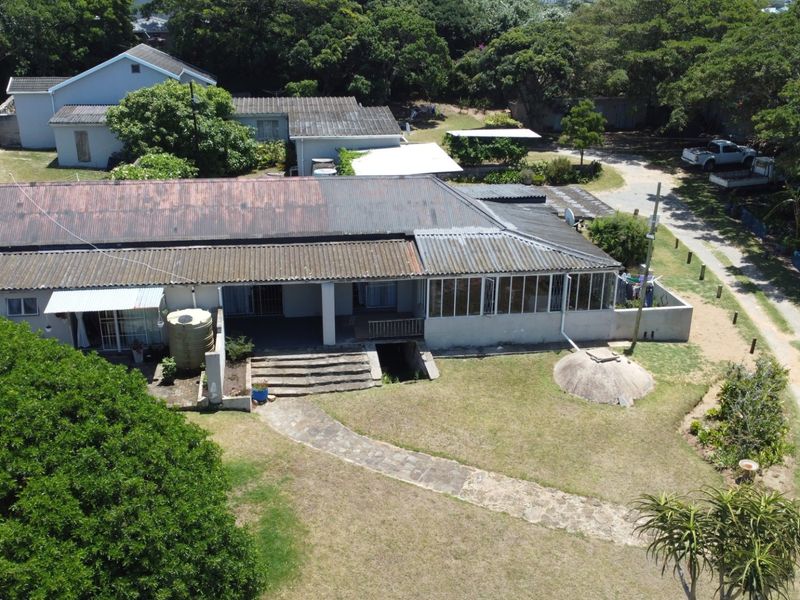 Aerial view of a townhouse property featuring a corrugated metal roof, stone pathway, and established garden surroundings.