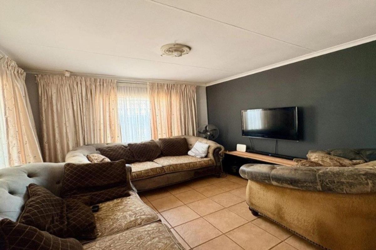 A comfortable living room featuring tiled flooring, a dark accent wall, and classic ceiling detailing, providing a functional space for relaxation.