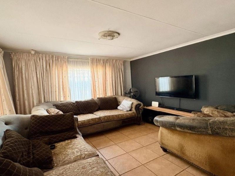 A comfortable living room featuring tiled flooring, a dark accent wall, and classic ceiling detailing, providing a functional space for relaxation.