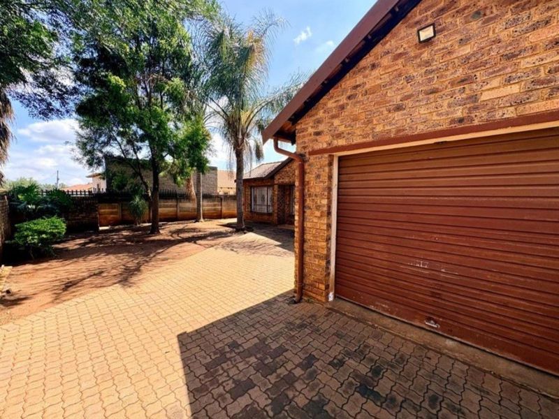Front exterior view of the property featuring a face brick facade, a roll-up garage door, and a paved driveway area.