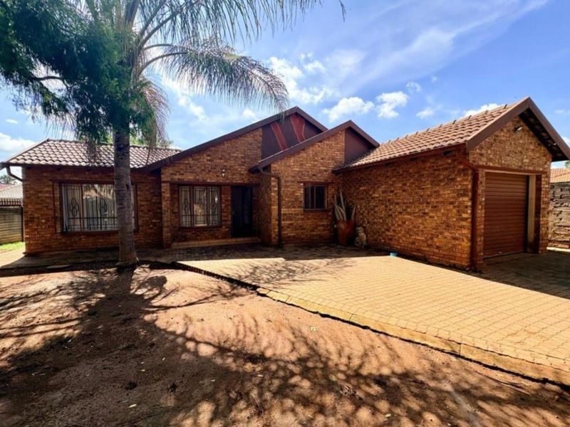 Front elevation of a face brick house featuring a tiled roof, paved driveway, and an integrated single garage.