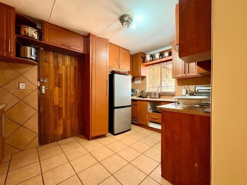 A functional kitchen featuring wooden cabinetry, tiled flooring, and a tiled backsplash, offering a traditional aesthetic with potential for modern updates.