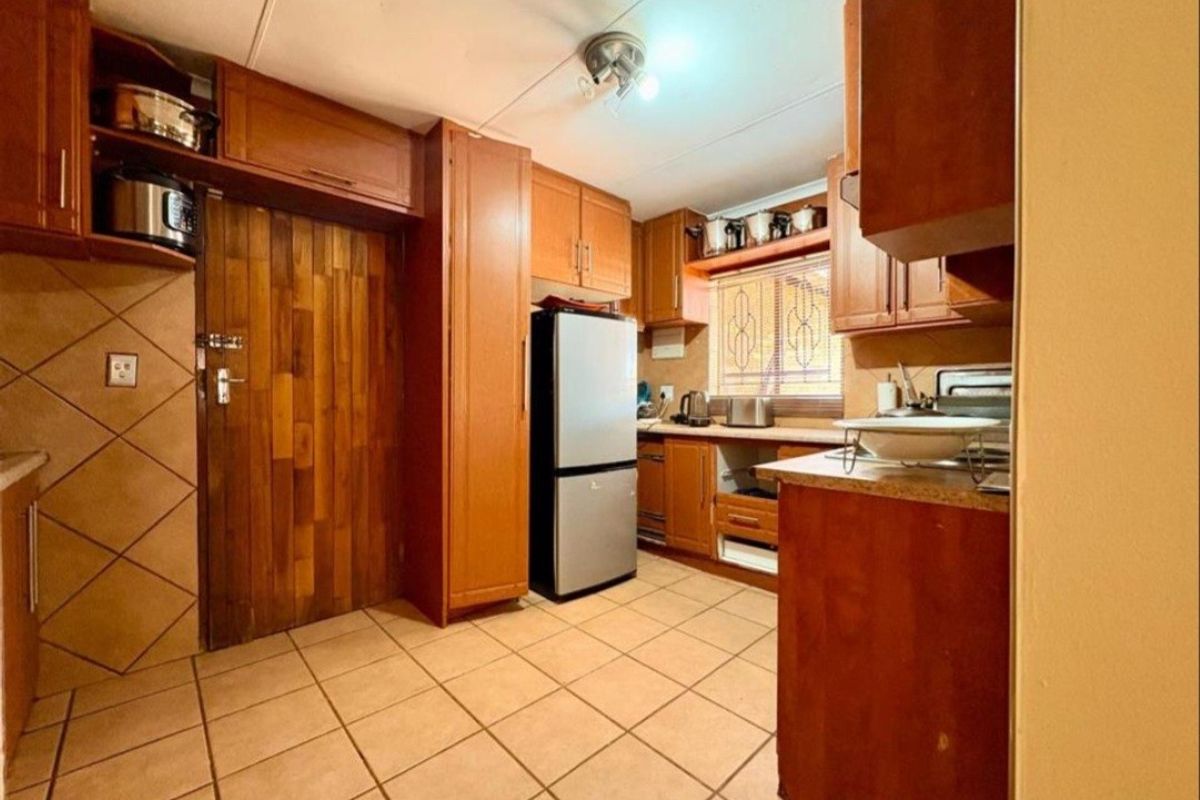 A functional kitchen featuring wooden cabinetry, tiled flooring, and a tiled backsplash, offering a traditional aesthetic with potential for modern updates.
