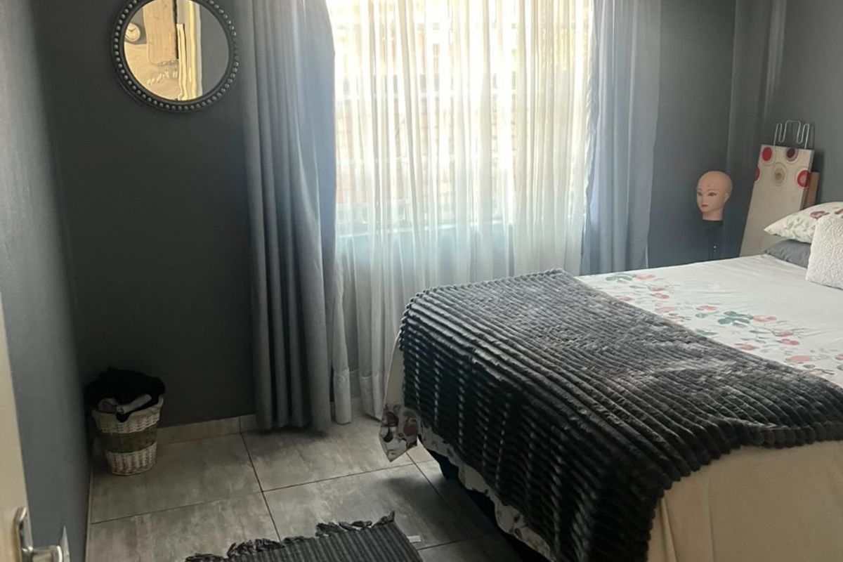 A bedroom featuring grey painted walls, tiled flooring, and decorative cornice detailing around the ceiling.