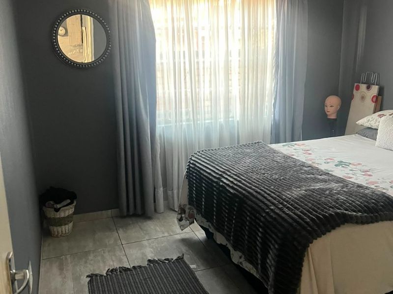 A bedroom featuring grey painted walls, tiled flooring, and decorative cornice detailing around the ceiling.