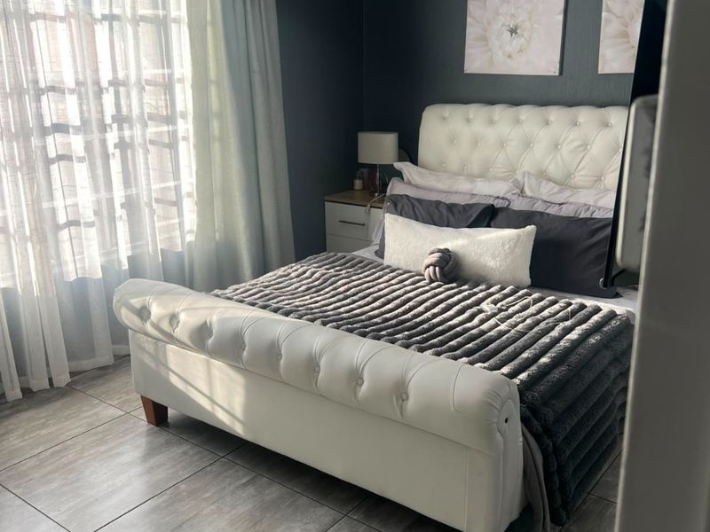 A well-maintained bedroom featuring modern grey floor tiles, crown molding, and a decorative tongue and groove ceiling finish.