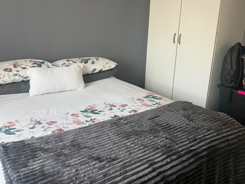 A bedroom featuring a built-in wardrobe and a dark grey accent wall.