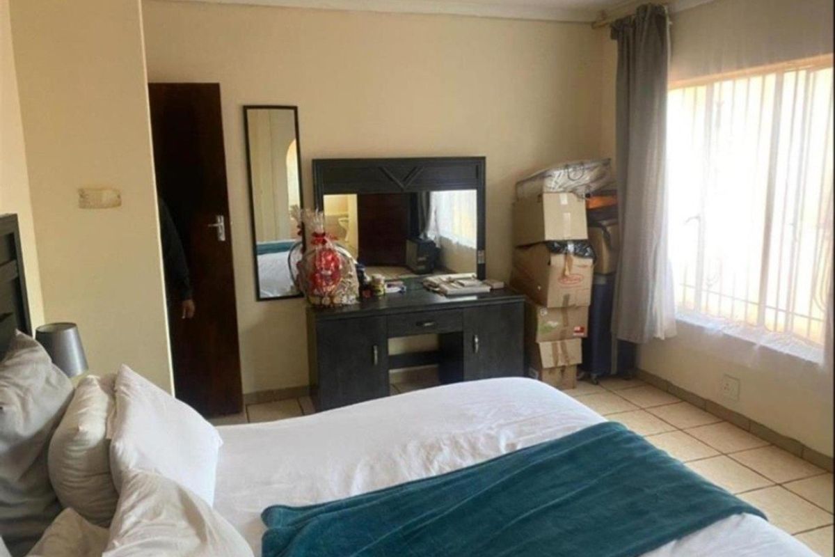 A standard bedroom featuring tiled flooring and a window with curtain rails, providing a functional space for rest.