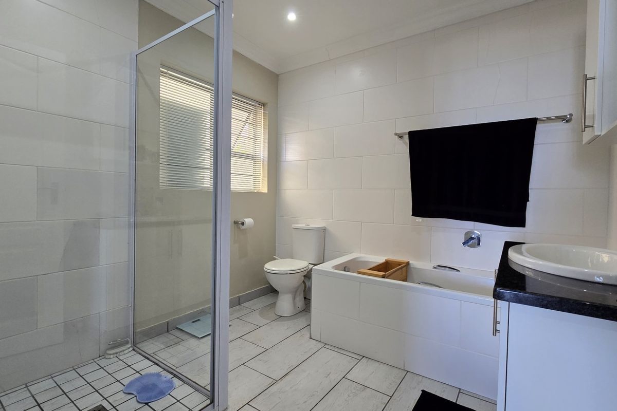 A modern, well-maintained bathroom featuring a glass-enclosed shower, a built-in bathtub, and a vanity with a countertop basin.