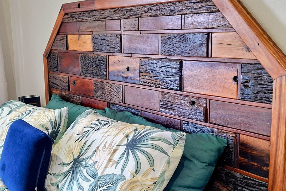 A close-up view of a bedroom featuring a custom-crafted wooden headboard with a textured, multi-tonal timber design.
