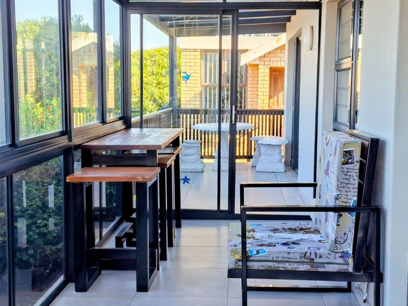 A bright, enclosed patio featuring tiled flooring, large glass sliding doors, and a modern aluminum frame, offering a seamless transition to the outdoor area.
