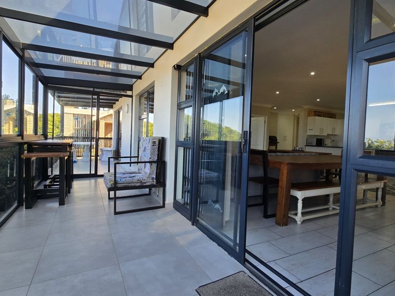 Enclosed patio area featuring a glass roof, tiled flooring, and large sliding glass doors providing seamless access to the interior living space.