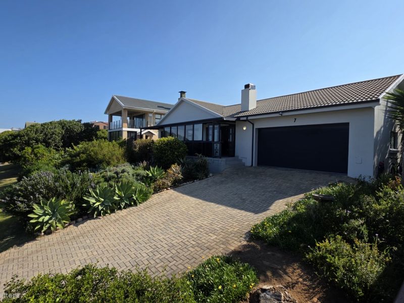 A well-maintained single-story residential property featuring a paved driveway, double garage, and established garden landscaping.