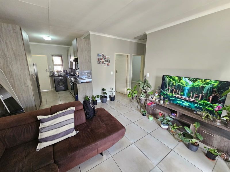 Open-plan living area featuring tiled flooring, integrated kitchen cabinetry, and a laundry nook, creating a functional and connected living space.