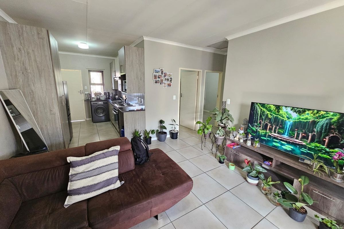 An open-plan living area featuring tiled flooring, a modern kitchen with built-in cabinetry, and direct access to adjacent rooms.