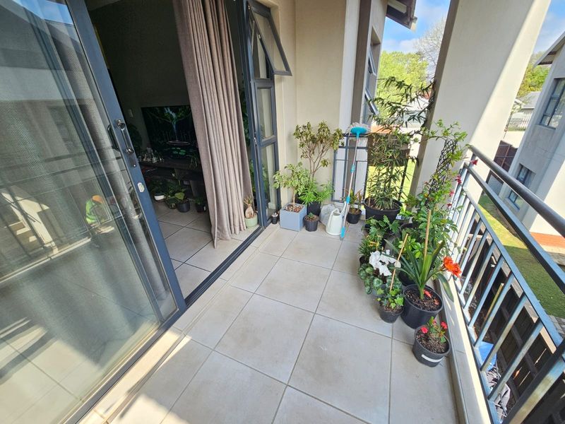 A covered balcony featuring tiled flooring and a metal balustrade, providing a seamless transition from the interior living space to the outdoors.