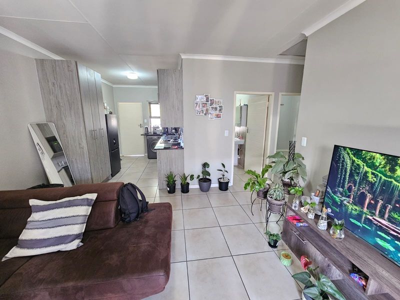 Open plan living area featuring tiled flooring and integrated kitchen cabinetry, providing a functional and connected layout for modern townhouse living.