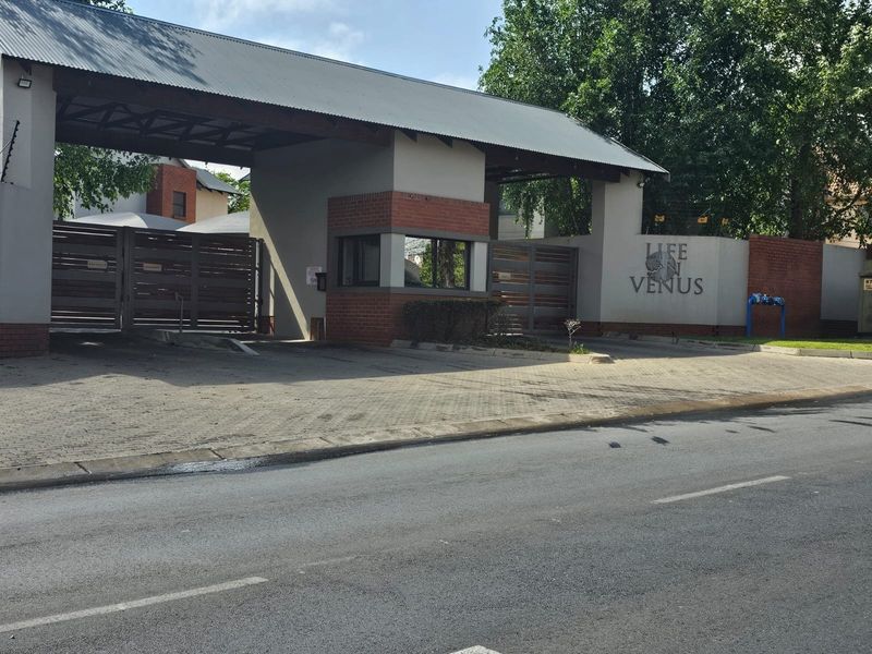 The secure entrance gate and guard house of the Life on Venus residential complex, featuring brick masonry and paved access.