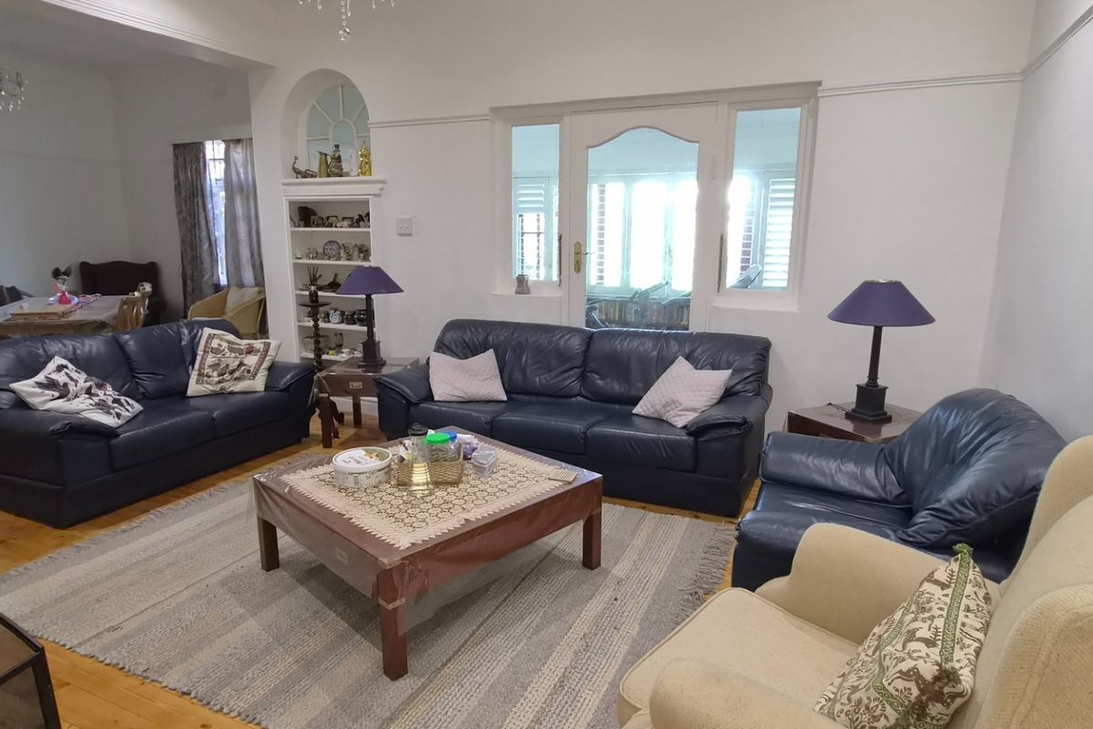 Spacious living room featuring original hardwood flooring, built-in shelving, and classic architectural details including picture rails and an arched doorway.