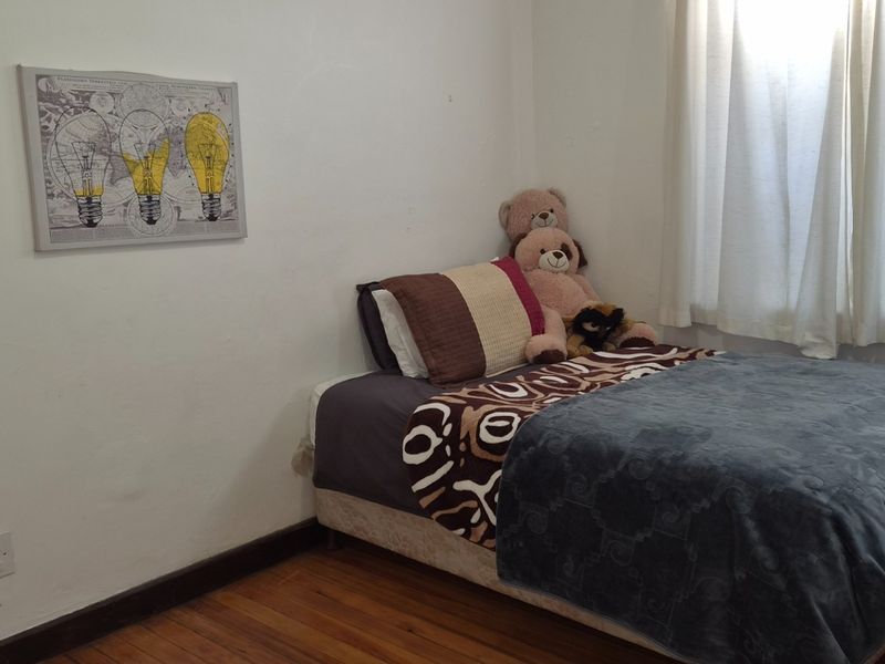 A compact bedroom featuring hardwood flooring and neutral wall finishes, offering a functional space with natural light from the window.