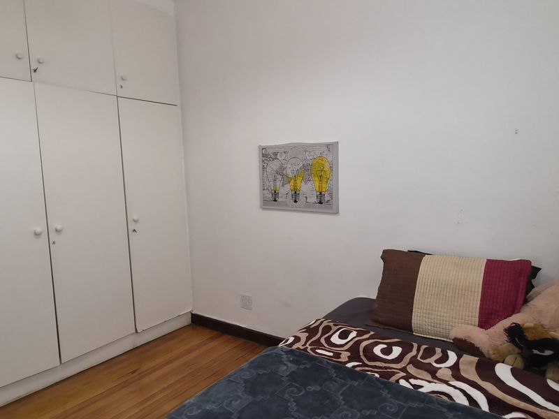 A bedroom featuring hardwood flooring and ample built-in cupboard storage space.