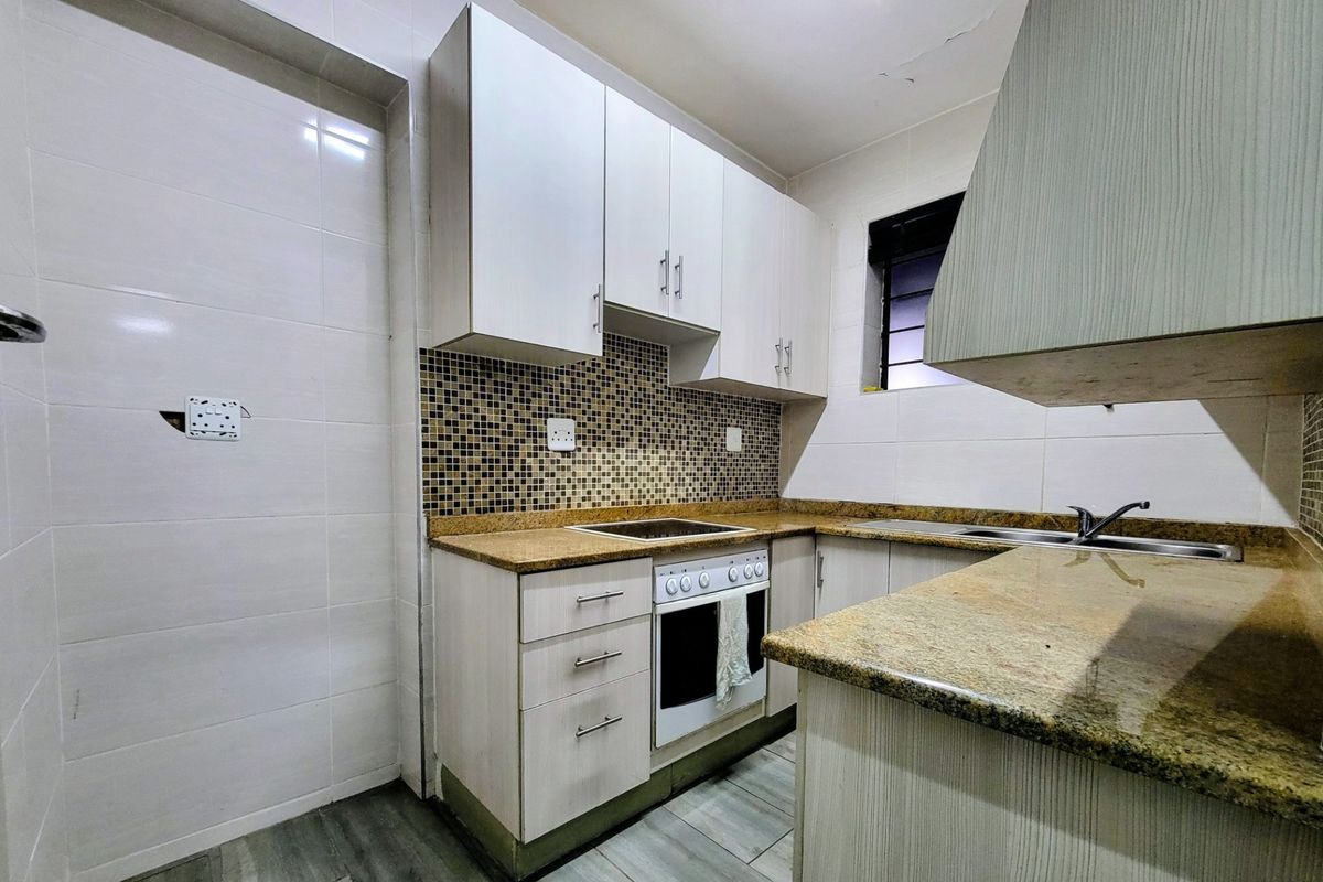 A compact kitchen featuring granite countertops, mosaic backsplash, built-in cabinetry, and integrated appliances, requiring minor ceiling and electrical repairs.