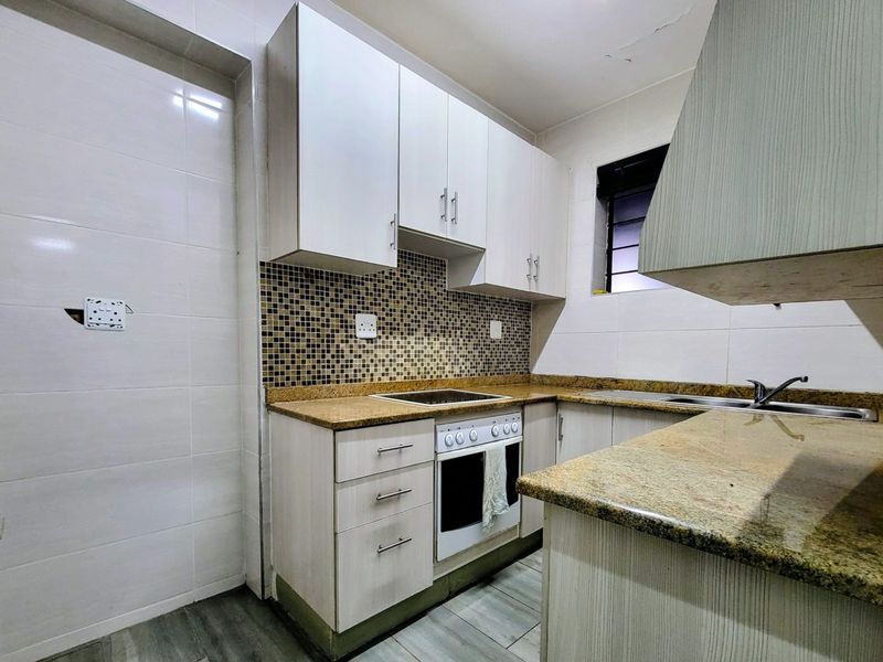 A compact kitchen featuring granite countertops, mosaic backsplash, built-in cabinetry, and integrated appliances, requiring minor ceiling and electrical repairs.