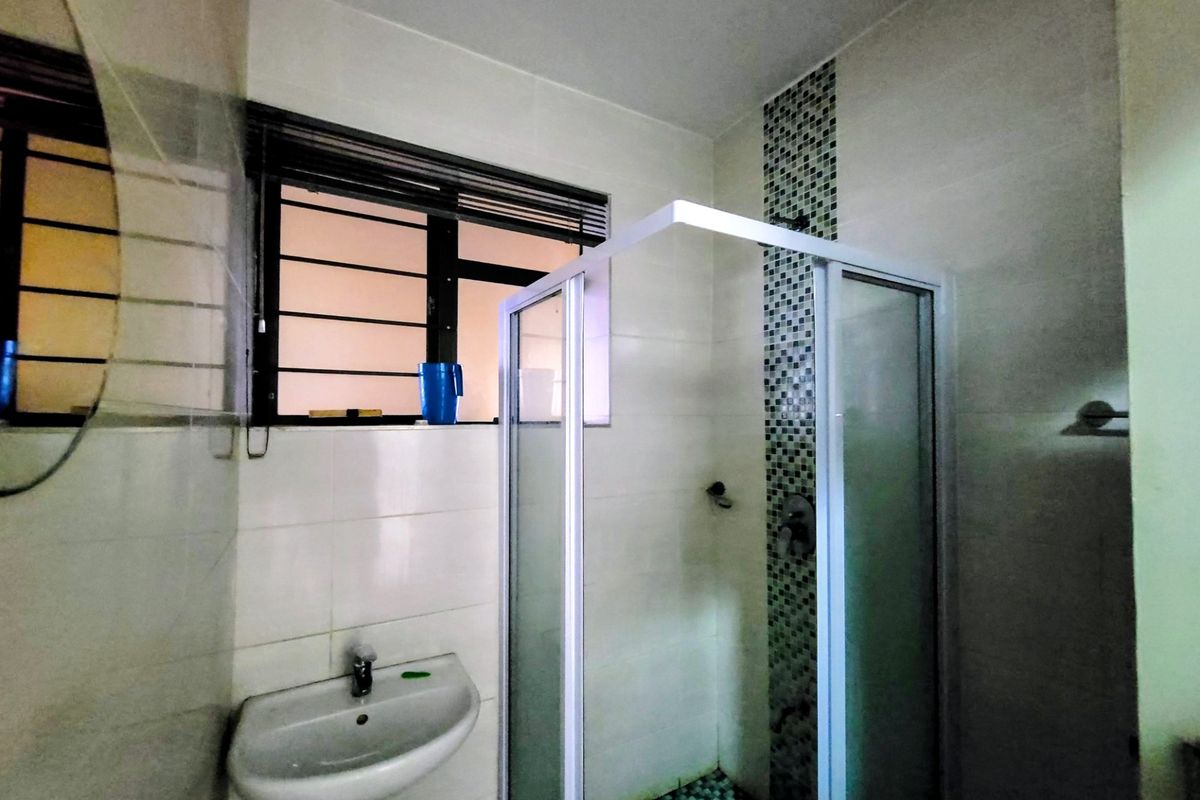 A functional bathroom featuring a shower enclosure, wall-mounted basin, and a decorative mosaic tile accent wall.