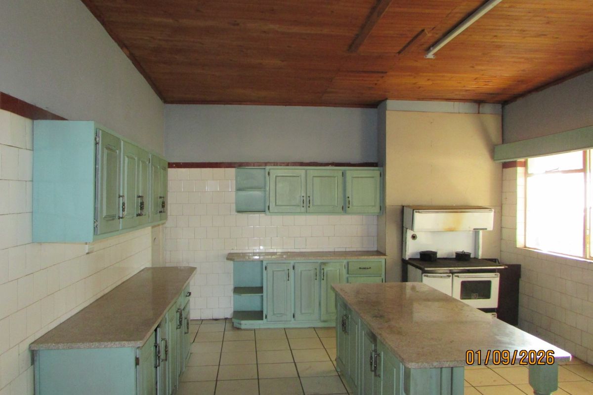 Spacious kitchen featuring dated cabinetry, stone countertops, tiled flooring, and a timber ceiling, offering significant potential for a modern renovation.