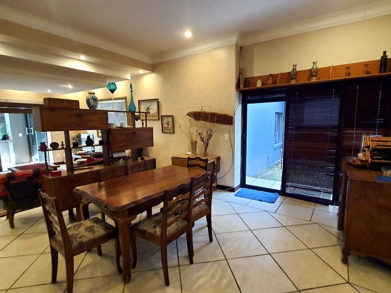 Spacious open-plan living and dining area featuring ceramic tile flooring, recessed lighting, and direct access to an outdoor patio through sliding glass doors.