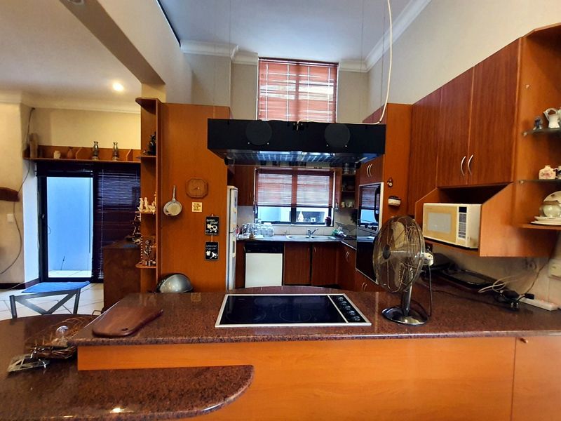 Open plan kitchen and living area featuring wood-finish cabinetry, granite countertops, integrated appliances, and direct access to an outdoor patio area.