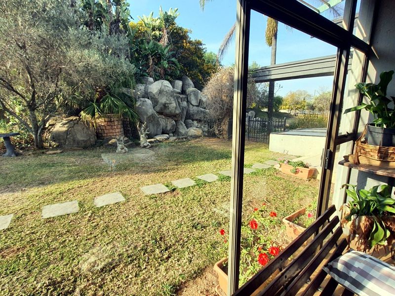 A view from a covered patio looking out onto a landscaped garden featuring a rockery and paved stepping stones.