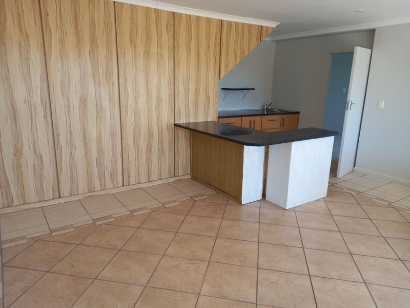 Open plan living area featuring a kitchen with built-in cabinetry, a breakfast bar, and tiled flooring throughout.