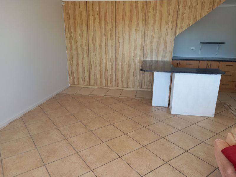 Open plan living and kitchen area featuring tiled flooring, built-in cabinetry, and a breakfast bar, offering a blank canvas for renovation.