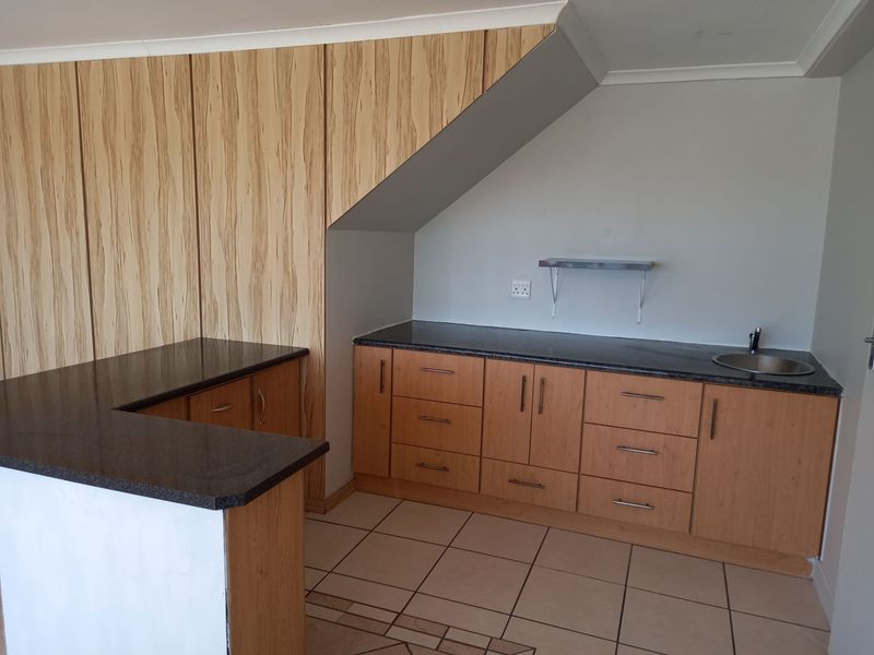 A clean, functional kitchen area featuring light wood-grain cabinetry, dark granite countertops, and tiled flooring, offering a neutral space ready for personalization.