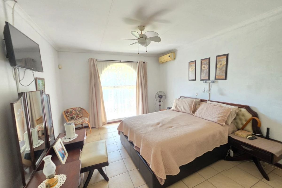 A bedroom featuring tiled flooring, a ceiling fan, and a wall-mounted air conditioning unit, with access to a sliding glass door.