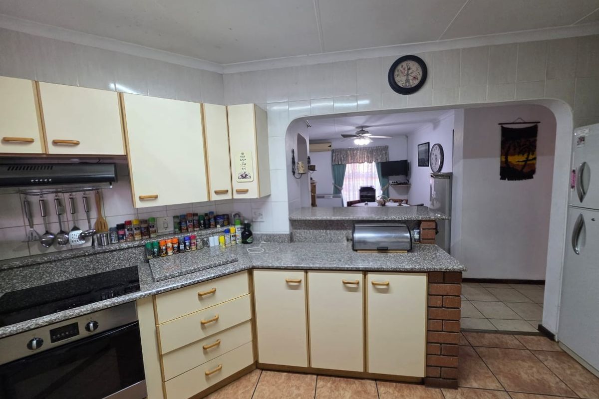 A functional kitchen featuring built-in cabinetry, granite countertops, and a breakfast bar opening into the adjacent living area.