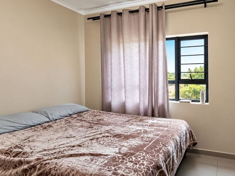 A well-maintained bedroom featuring tiled flooring, a built-in wardrobe, and an aluminium-framed window with natural light.