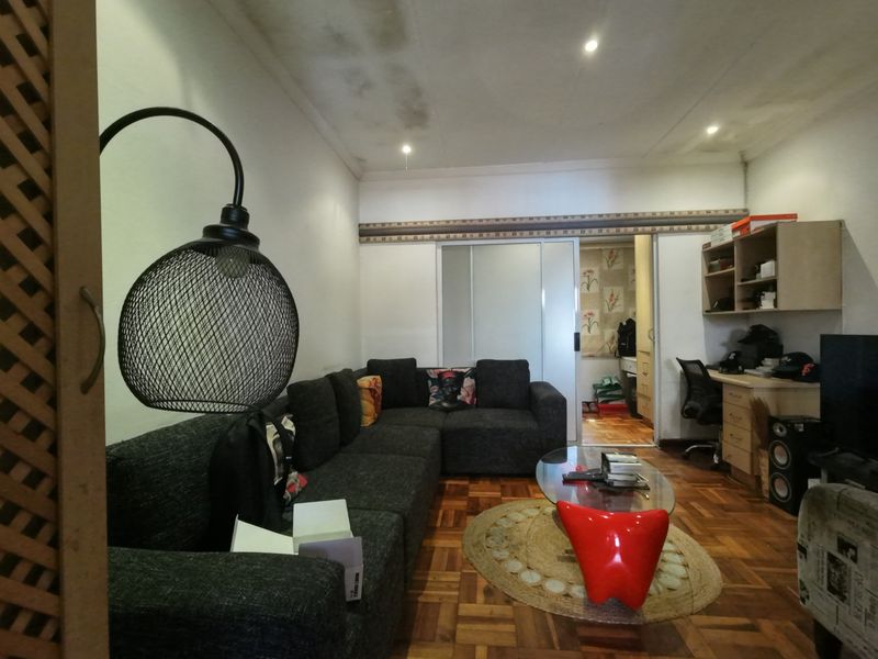 Living room featuring parquet flooring, recessed lighting, and a built-in workspace, with visible ceiling water staining requiring attention.