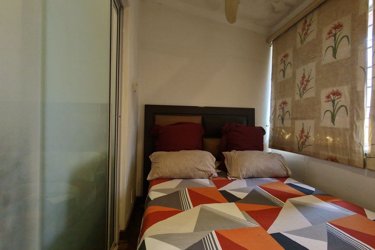 A compact bedroom featuring a ceiling fan and sliding door access, showing visible signs of ceiling water damage.