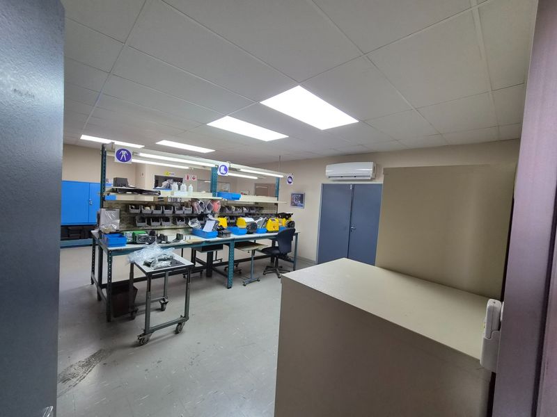Industrial utility or workshop space featuring a suspended ceiling, split-system air conditioning, and integrated workbench area with storage.