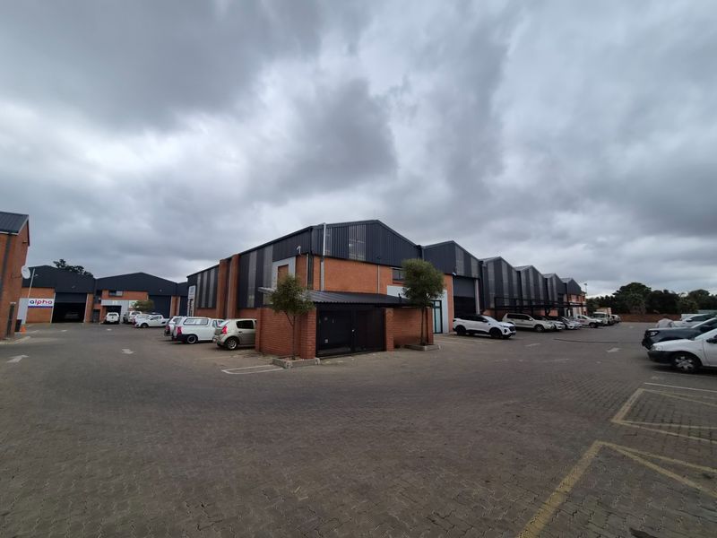 Exterior view of an industrial complex featuring brick facades, metal roofing, and a paved parking area.