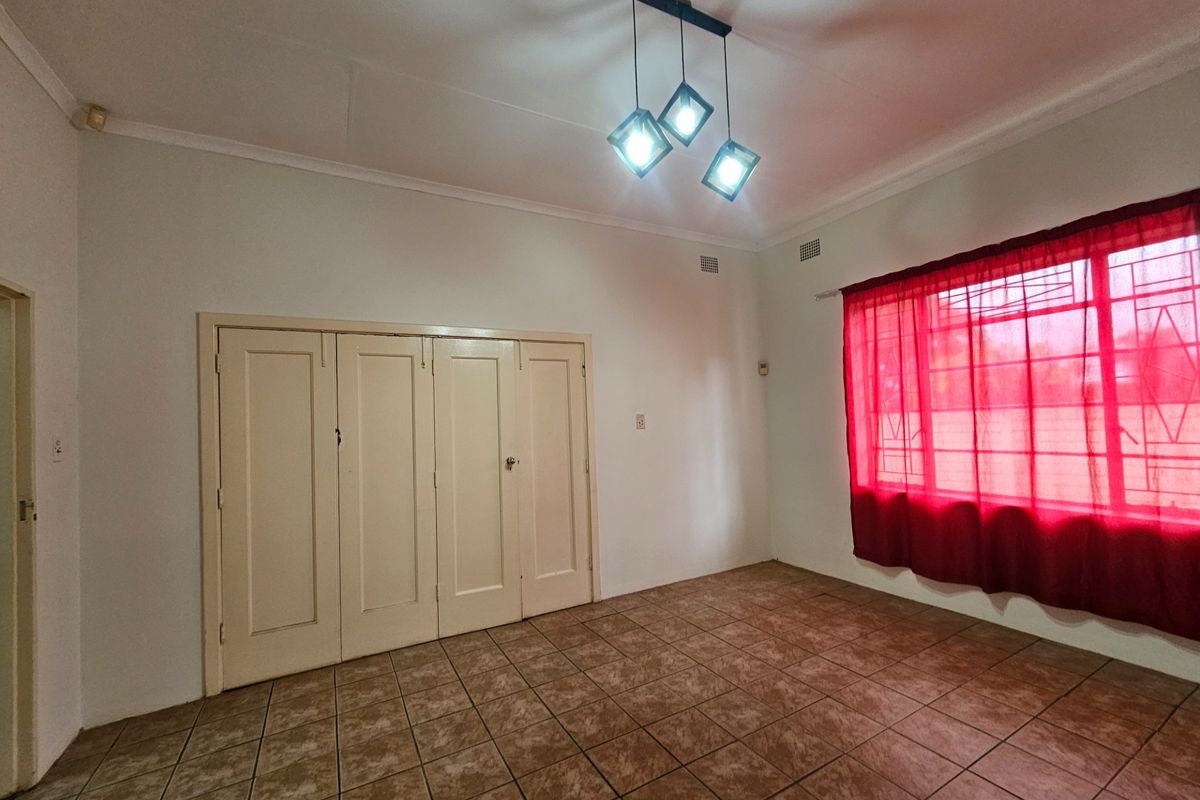 A vacant bedroom featuring tiled flooring, built-in cupboards, and a modern geometric ceiling light fixture.